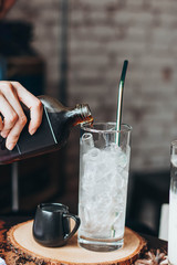 Ice coffee in a tall glass over and coffee beans on a old rustic wooden table.