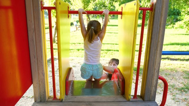 Mother And Baby Play On Playground. Little Kid Laughs And Enjoys The Playground In The Park. Child Plays With Mom On The Street.