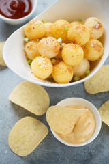 Close-up of fried potato balls and potato chips with dipping sauces, vertical shot, selective focus
