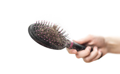Hand holding the comb with the fallen hair. Close up. Isolated on a white background