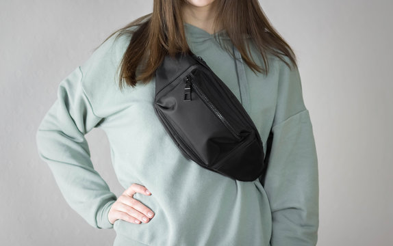 Girl in a hoodie with a bag on her chest. Close up. Isolated on a gray background