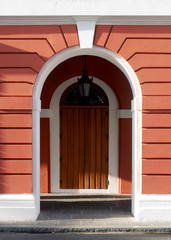 Double arched doors within outer archway set into an orange wall with white trim along the cobblestone sidewalks of old town San Juan.