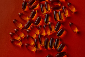 fish oil capsules on red background close-up