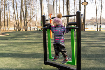 Obraz premium little girl preschooler is engaged on a street exercise machine in a park