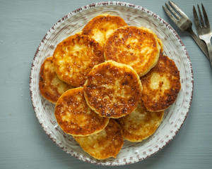 Plate with pre-baked cheesecakes on a round ceramic plate, vintage dessert forks on a gray table