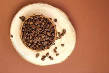 coffee beans in a  round cup on a cut of a tree on a dark brown background.Coffee drink.Coffee beans in a minimalist style.top view