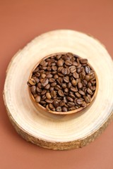coffee beans in a wooden  cup on a cut of a tree on a dark brown background.Coffee drink.Coffee beans in a minimalist style.top view