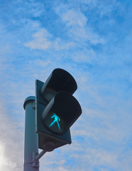 Green traffic light with clouds in background