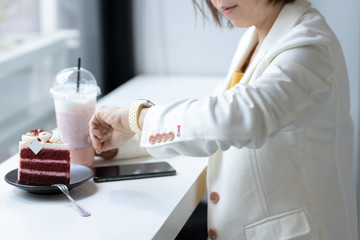 female look smartwatch to managing time for next meeting sitting at cafe resting in cozy cafeteria interior