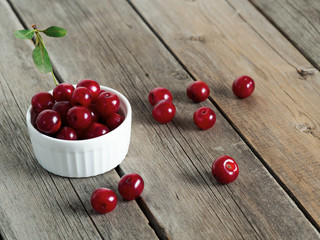 Red ripe cherries on rustic weathered wooden table.