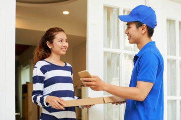 Obraz premium Cheerful courier giving pizza to young woman who ordered it online