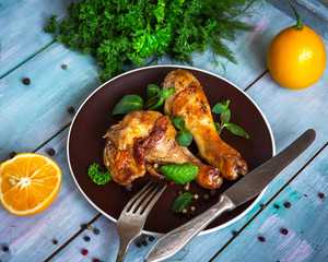 tasty baked drumsticks for a hearty lunch with herbs and lemon on a wooden board table