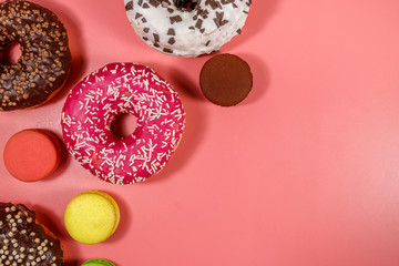 Tasty donuts and macaroons on pink background. Top view, copy space