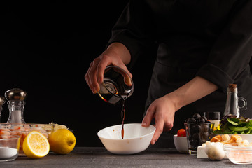 Chef prepares salad dressing by pouring soy sauce to camellia shrimp. Freezing in motion, preparing...