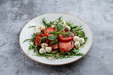 Classic italian caprese with ripe tomatoes, mozzarella cheese, basil and pesto sauce.