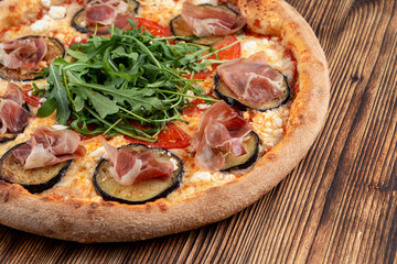 Italian pizza with grilled eggplant, arugula, tomatoes, parma ham and sirtaki cheese