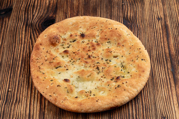 Soft fluffy focaccia with garlic and rosemary on wooden table