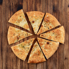 Soft focaccia with garlic and rosemary, sliced in triangled on wooden table