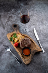 Beef steak and baked potatoes with grated parmesan cheese and nutmeg on a wooden cutting board