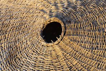 Background of weaving from natural materials. Woven from branches, the product lies on the sand.