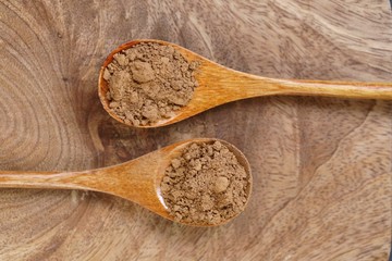 Dry guarana powder in wooden spoons on a wooden board