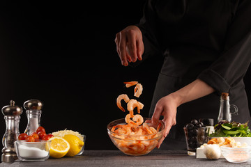 Cooking by a chef seafood, oriental or Asian cuisine. Shrimps cook with vegetables. Delicious and healthy food, gastronomy, and cooking. Recipe book. On a black background with space for design.