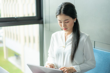 Smilling girl working at office on computer, using laptop.