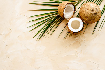 Fototapeta na wymiar Coconuts and leaves - tropical still life on beige background top-down copy space