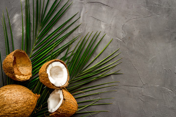 Fototapeta na wymiar Coconuts and leaves - tropical still life on grey background top-down copy space