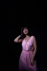 Obraz premium Portrait of a girl in pink dress in the light of colored lamps red, bright light and outline blue colors and dark background. Adorable fashionable sexy female model
