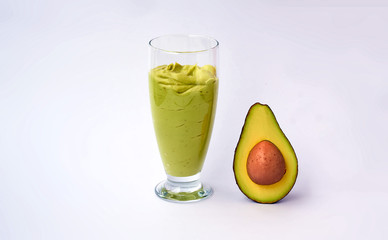 Fototapeta na wymiar A glass of avocado and spinach smoothies and half an avocado on white background. Fitness product. Dietary sports nutrition.