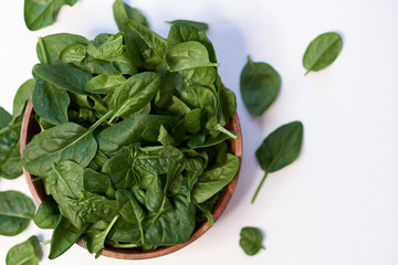 Fresh spinach in a wooden bowl isolated on white background top view photo