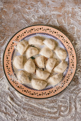 Raw dumplings are laid out on a plate, top view.2020