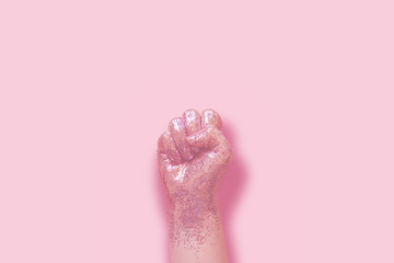 woman fist covered in pink glitter on pink background