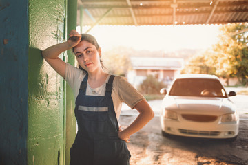 Gender equality. Portrait of a young brunette in uniform, leaning on the gate. In the background, a...