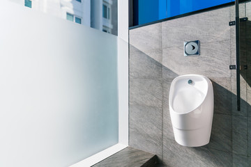 Sanitation white ceramic urinal in the men's bathroom with hygienic automatic water-saving...
