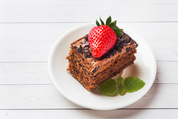 Truffle cake with chocolate and strawberries and mint on a white wooden table. Selective focus. Copy space