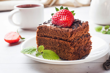 Truffle cake with chocolate and strawberries and mint on a white wooden table. Selective focus.
