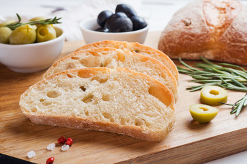 Italian ciabatta bread with olives and rosemary on a wooden Board.