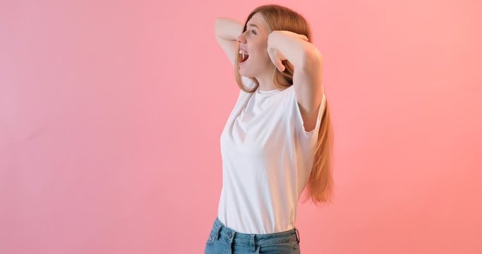 Portrait of an irritated woman in a white t-shirt , covering her ears and screaming from a terrible noise