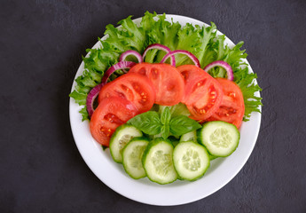 Healthy fresh vegetarian salad on a dish on black background. Flat lay composition