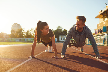 Young couple doing pushups in the stadium