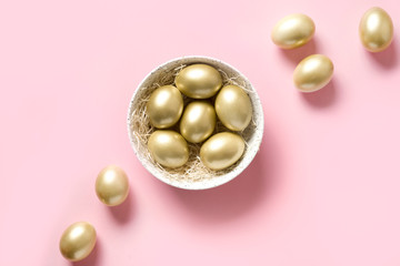Easter golden chicken eggs in bowl on pink. View from above. Minimal composition.