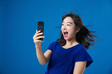 スマートフォンを持って驚く女性