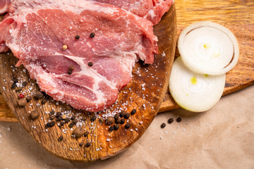 raw pork on wooden Board with pepper, onion, salt