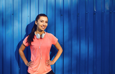 A smiling athletic girl stands on a blue background