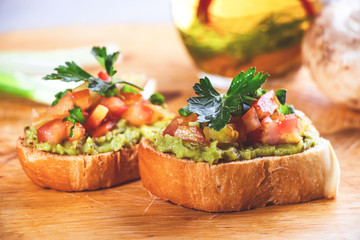 Bruschetta with avocado and tomatoes on a wooden cutting board