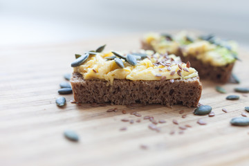 whole grain toast with avocado and flax and pumpkin seeds on a wooden board