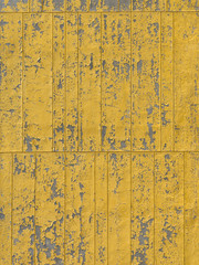 Weathered and scratched yellow paint on a concrete wall background.