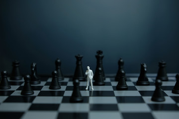 Business strategy conceptual photo -  miniature of businessman standing / waiting in the middle of chess piece on a chessboard